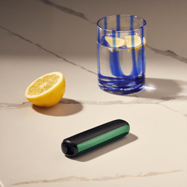 Ploom AURA priekšējais panelis Amazon Green piestiprināts pie ierīces uz galda
