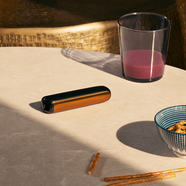 Ploom AURA priekšējais panelis Mango Sorbet piestiprināts pie ierīces uz galda
