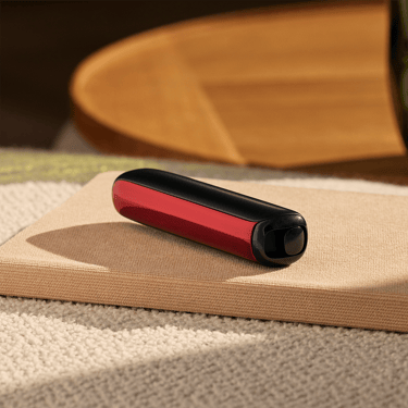 Ploom AURA priekšējais panelis Lava Red novietots uz galda
