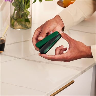 Roka uzliek Amazon Green aizmugurējo vāciņu uz Ploom AURA ierīces