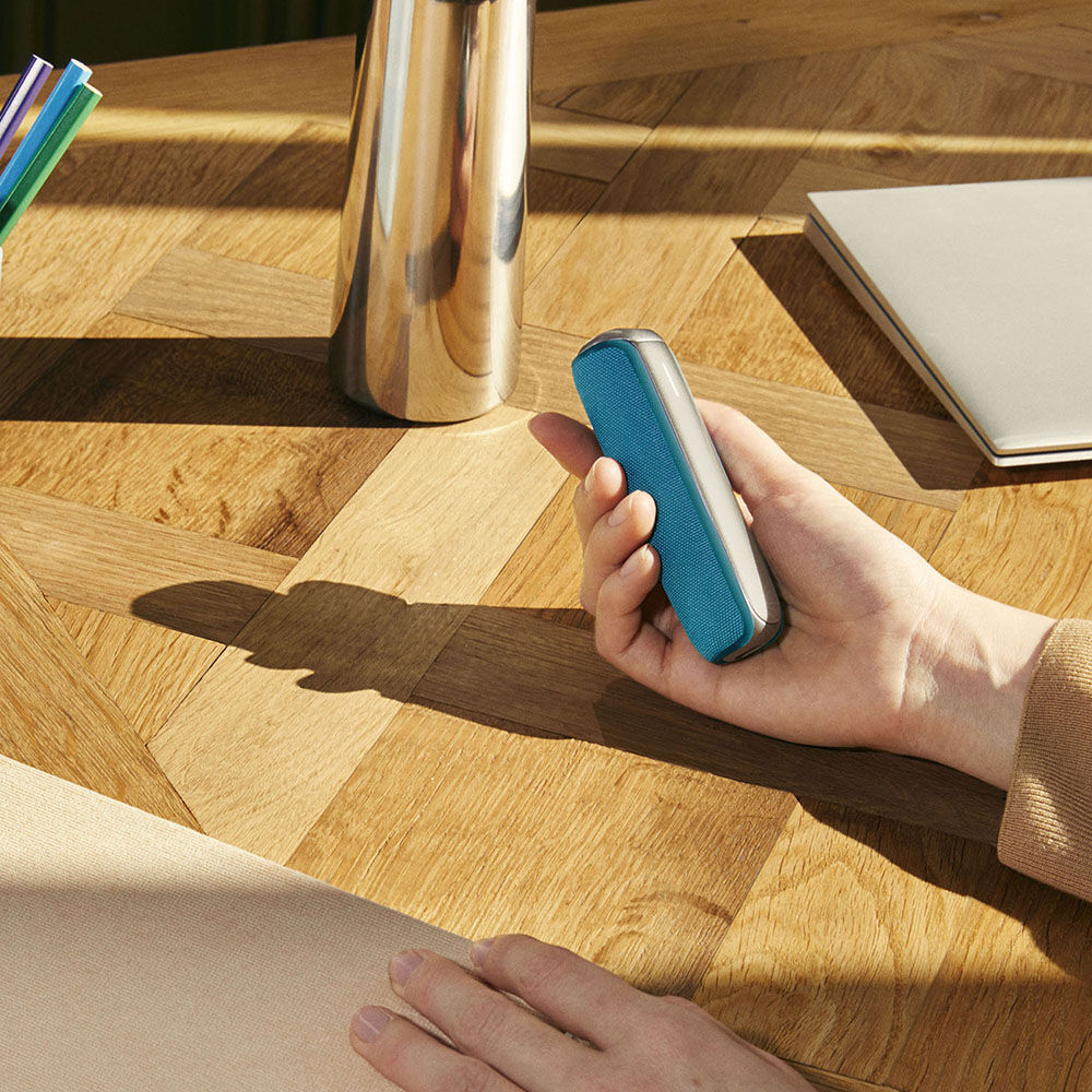 Roka tur Ploom AURA ierīci ar pievienotu Ocean Blue aizmugurējo vāciņu
